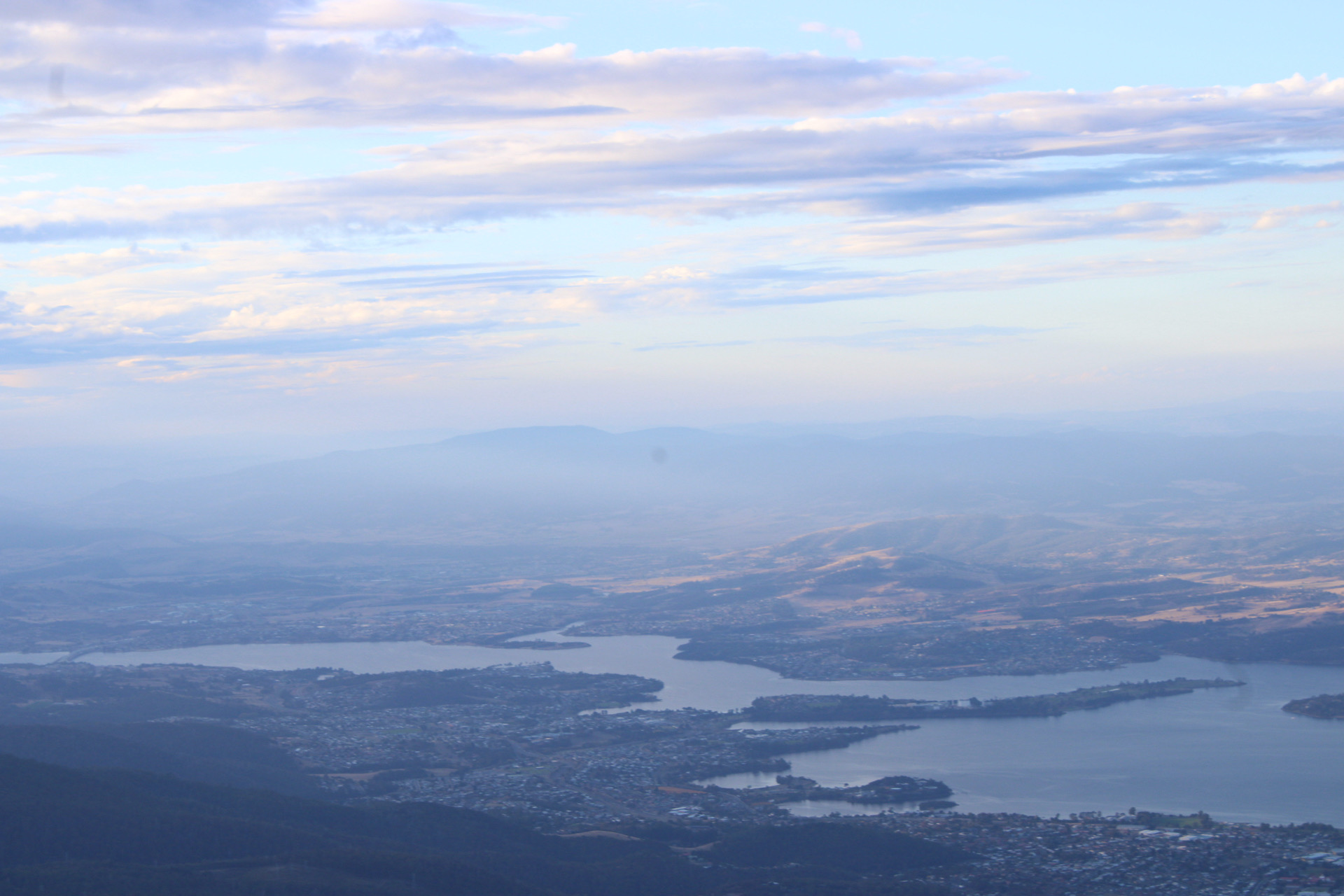 An expansive aerial landscape beneath a broad field of clouds