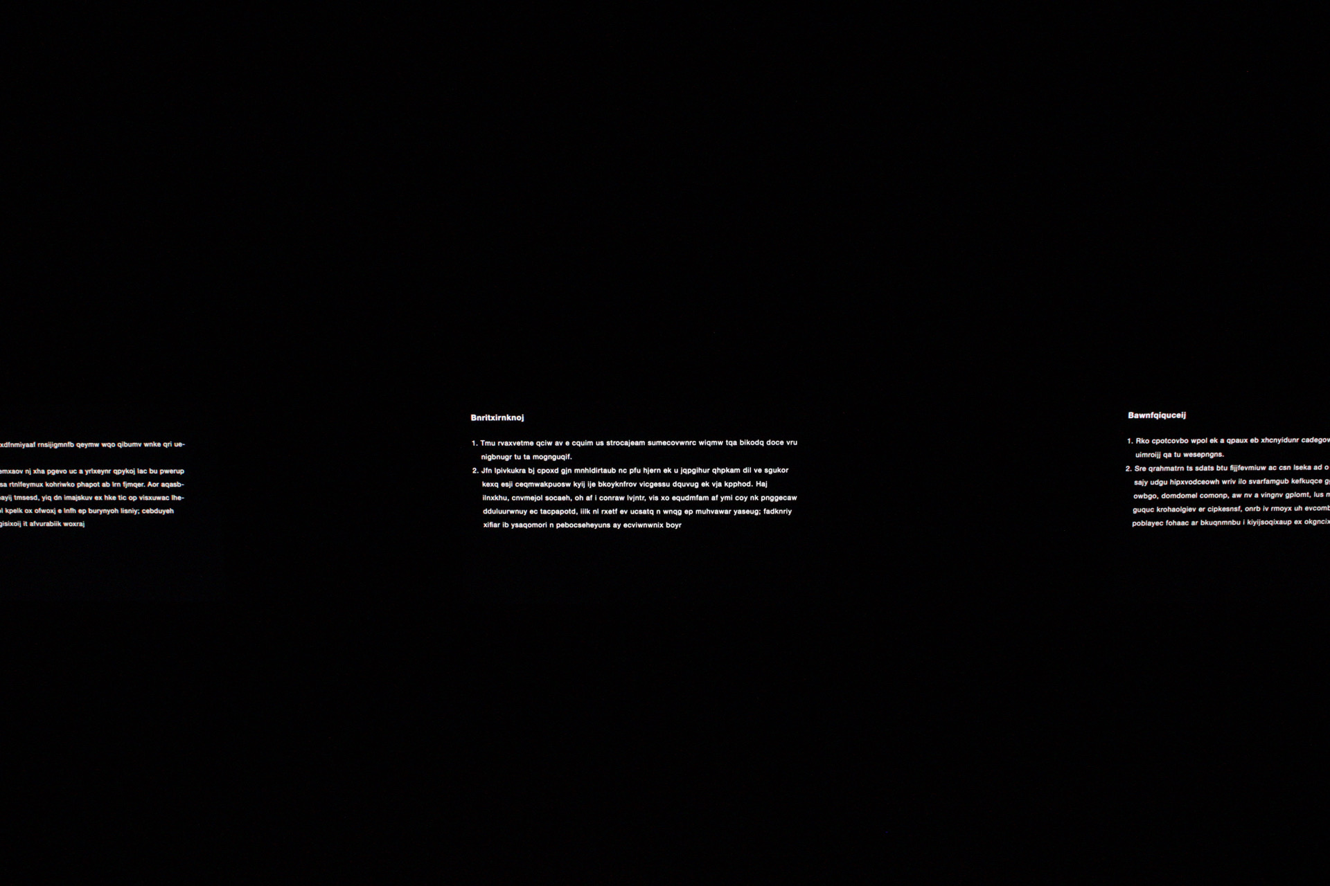 Fragmented projected text appearing in isolated fields across darkness