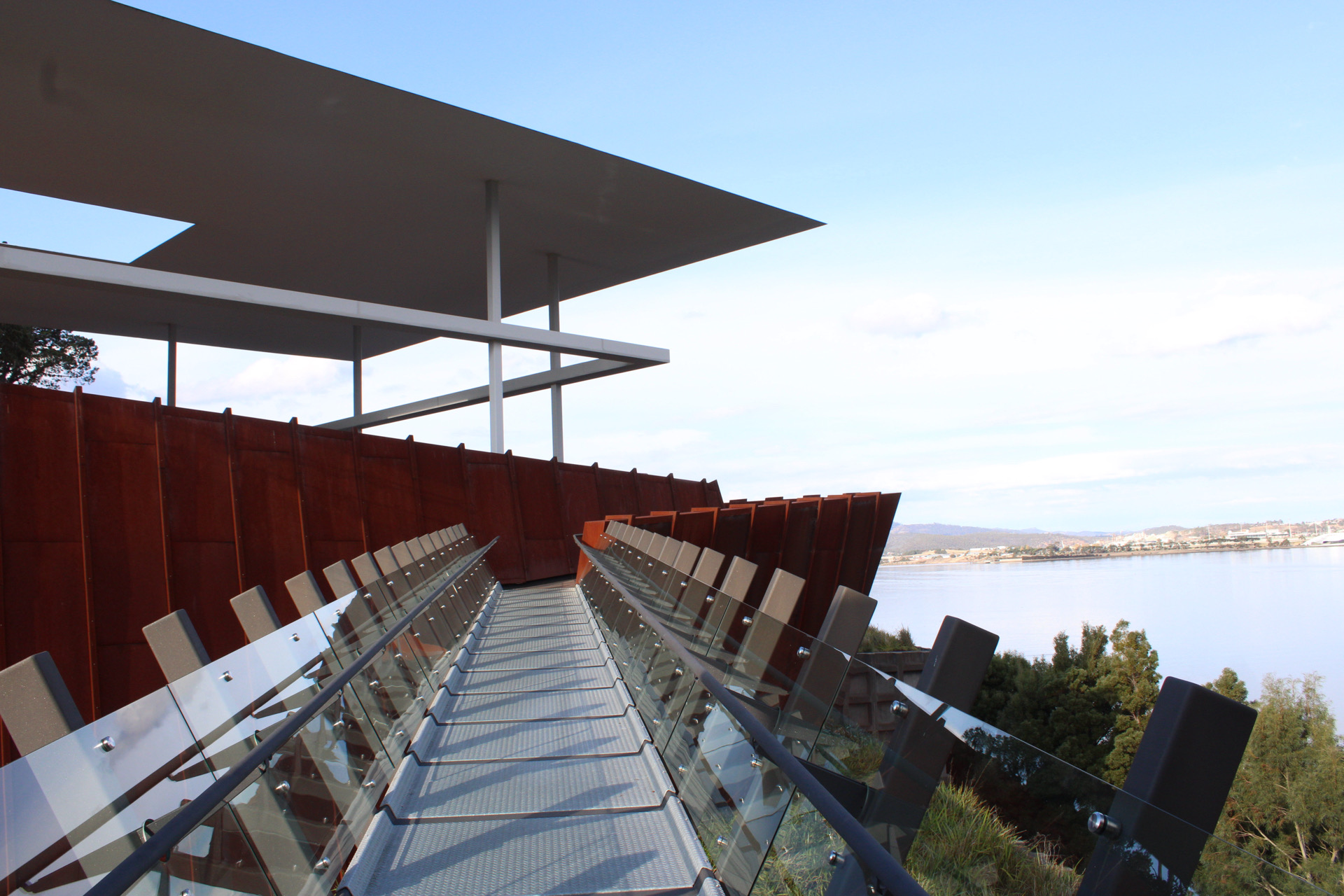 A diagonal architectural walkway framed by repeated rust colored panels